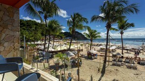 A beach with palm trees, umbrellas, and beach chairs.