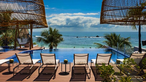 A poolside area with lounge chairs and a view of the ocean.