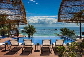 A poolside area with lounge chairs and a view of the ocean. - Pousada Bahia Tambor (Cairu)