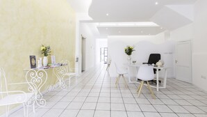 A modern, well-lit room with white furniture, a tiled floor, and a yellow accent wall. - La Gemma del Salento (Racale)