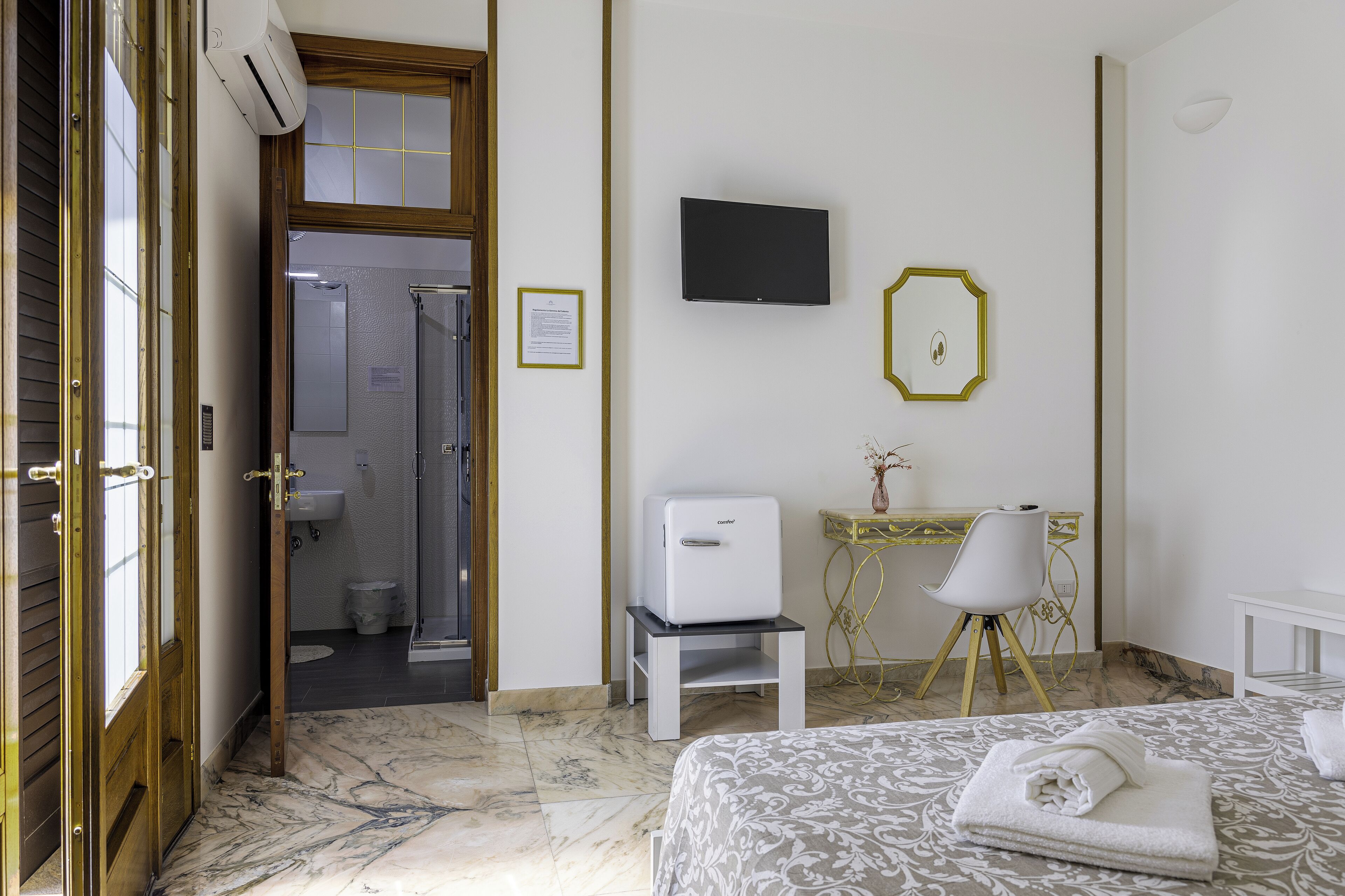 Ein Hotelzimmer mit Bett, Schreibtisch mit Stuhl, Fernseher und Duschbereich.