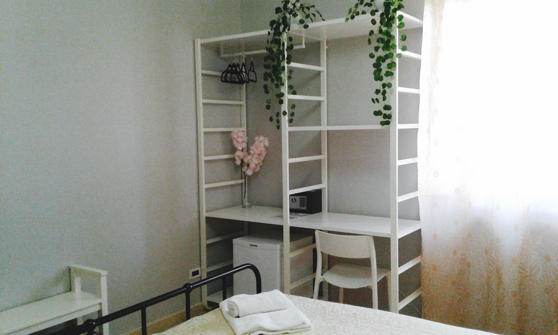A bedroom with a bed, a bedside table, a chair, a wardrobe, and a small desk with a chair.