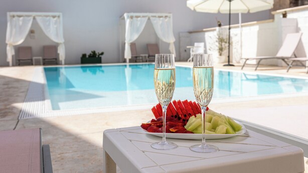 A poolside setting with two champagne flutes, a fruit platter, and a white table. - La Gemma del Salento (Racale)