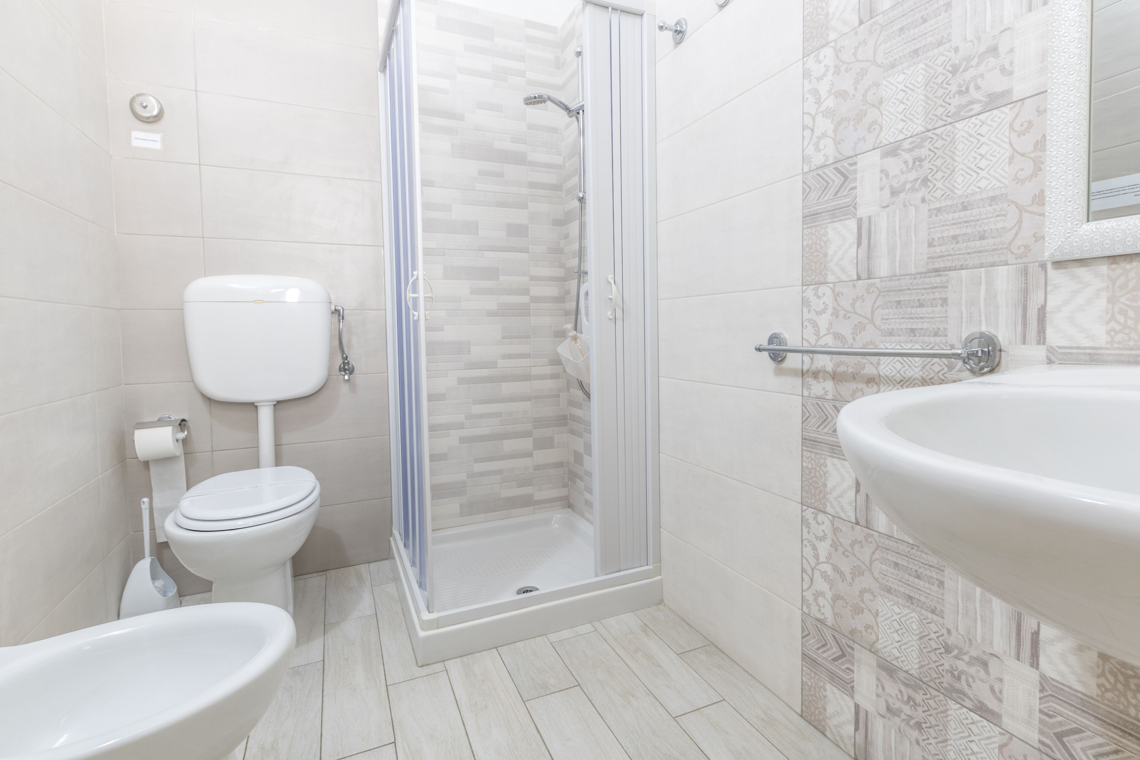 A modern bathroom with a toilet, bidet, shower, and sink.