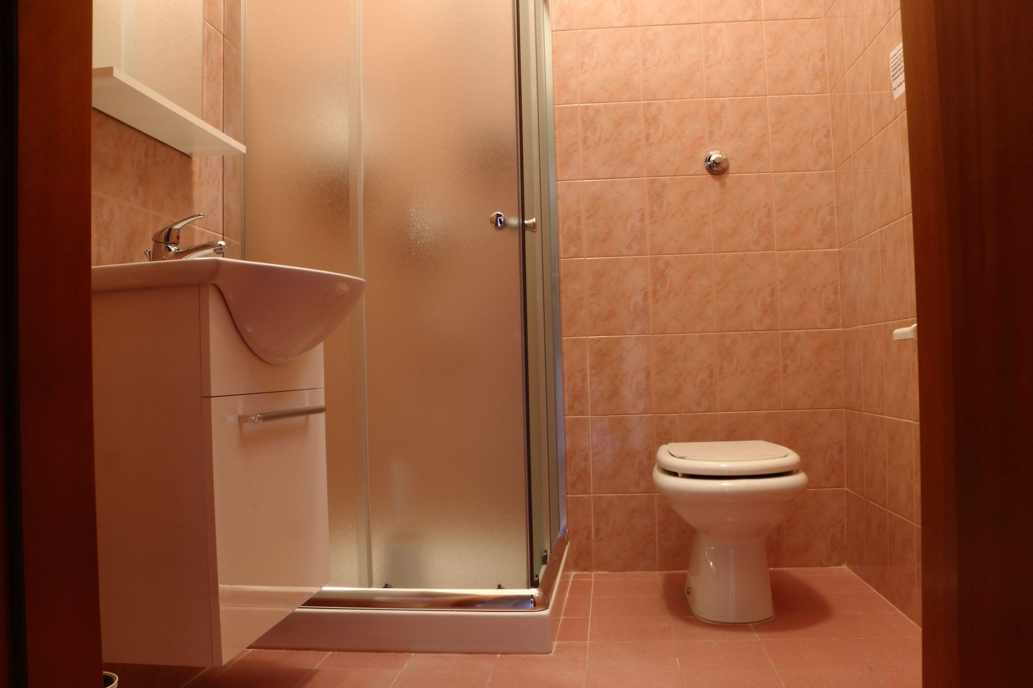 A bathroom with a glass shower enclosure, a sink, and a toilet.