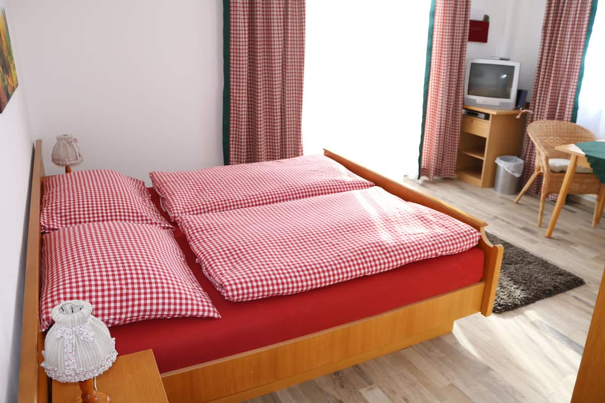 A bedroom with a bed, a desk, a chair, and a television.