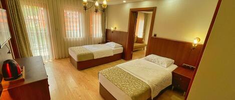 Quarto de hotel com duas camas, uma escrivaninha, chaleira e um candelabro.