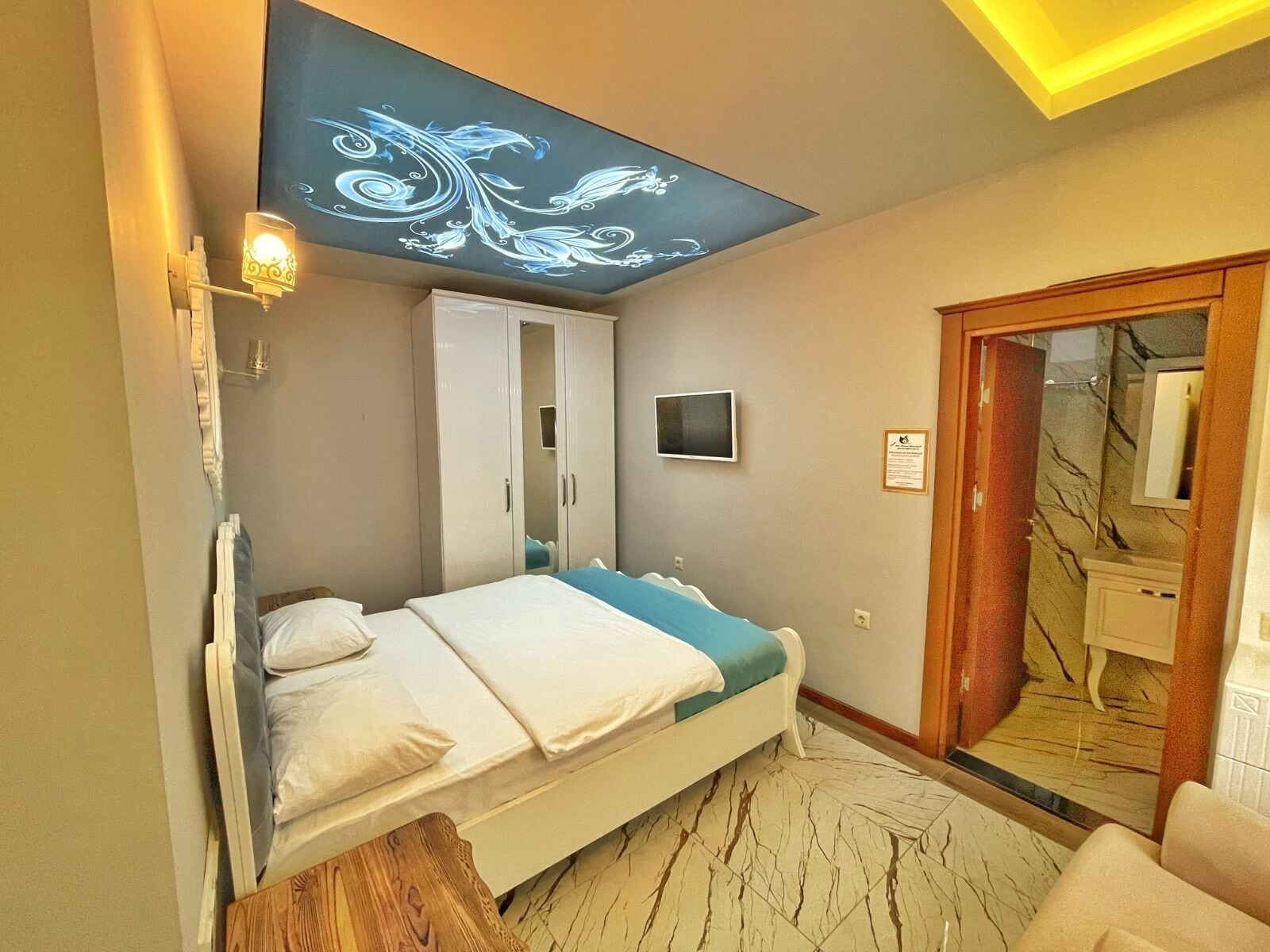 A bedroom with a bed, wardrobe, TV, and a mirror.