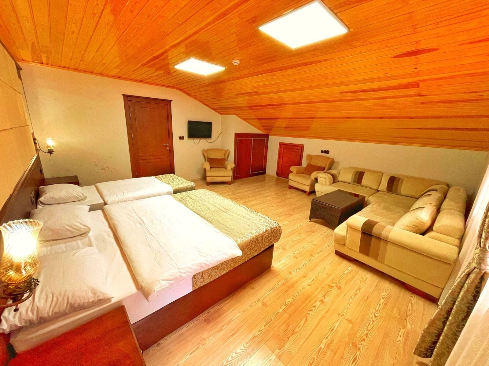 A bedroom with a large bed, a sofa, a chair, and a TV.