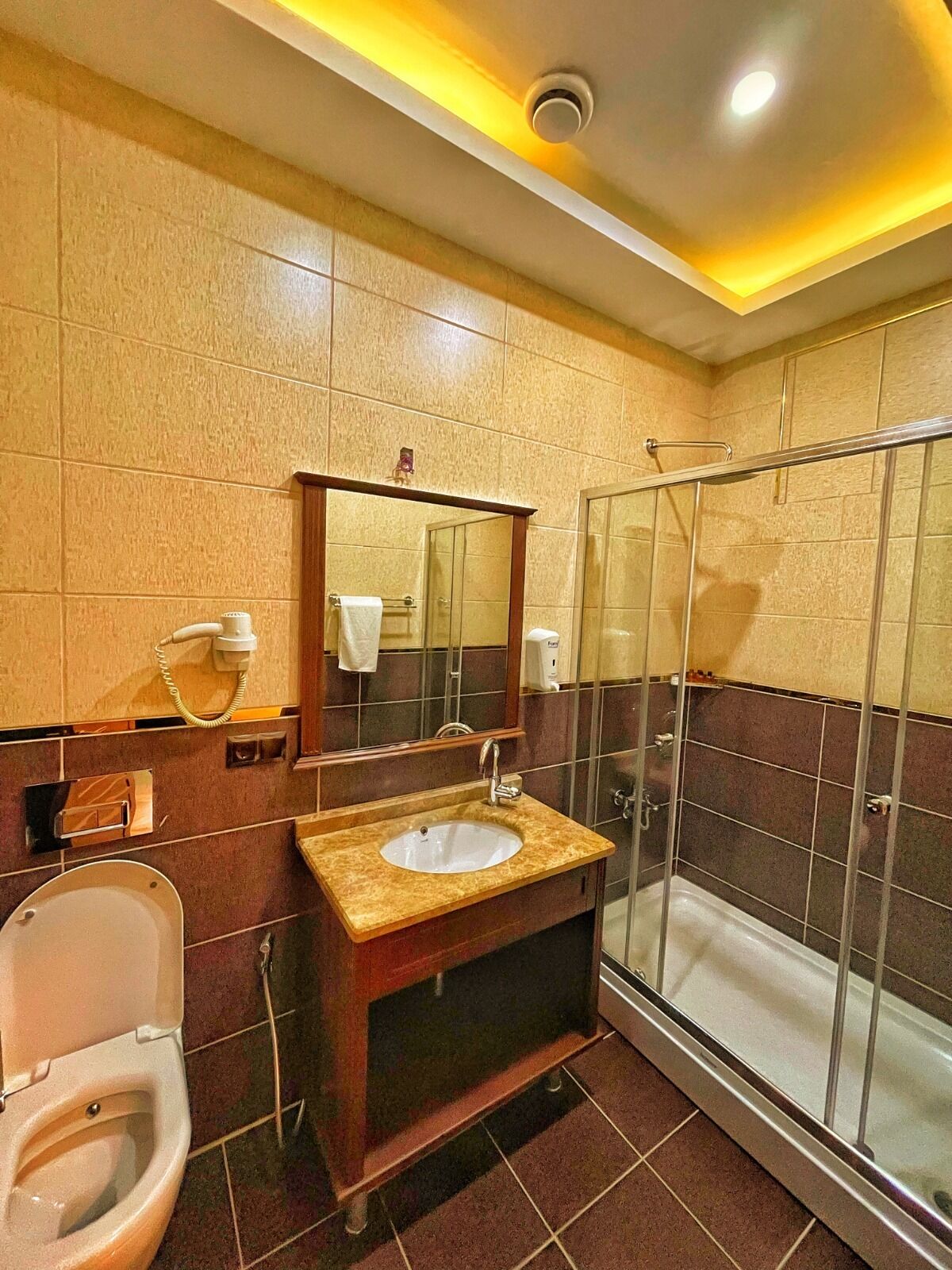Un baño con inodoro, lavabo, espejo y cabina de ducha de vidrio.