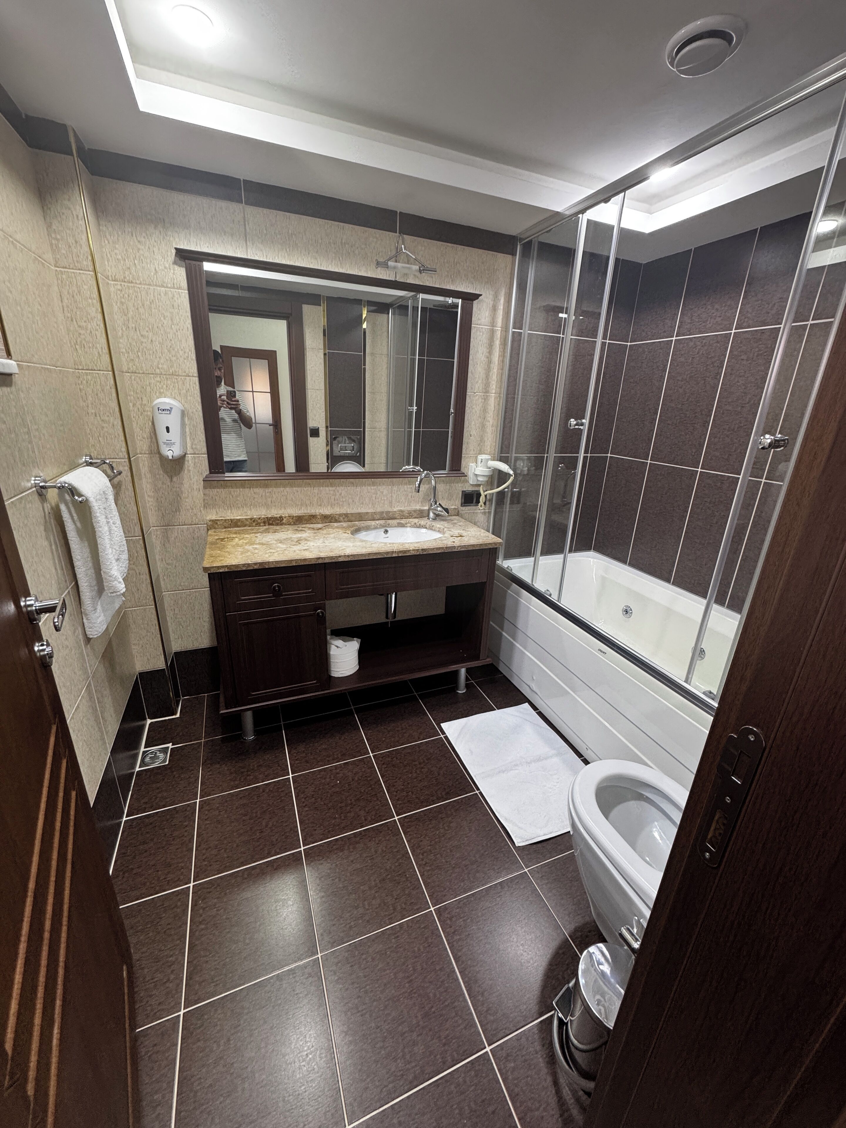 Een moderne badkamer met een grote spiegel, een wastafel, een toilet en een douchehoek.