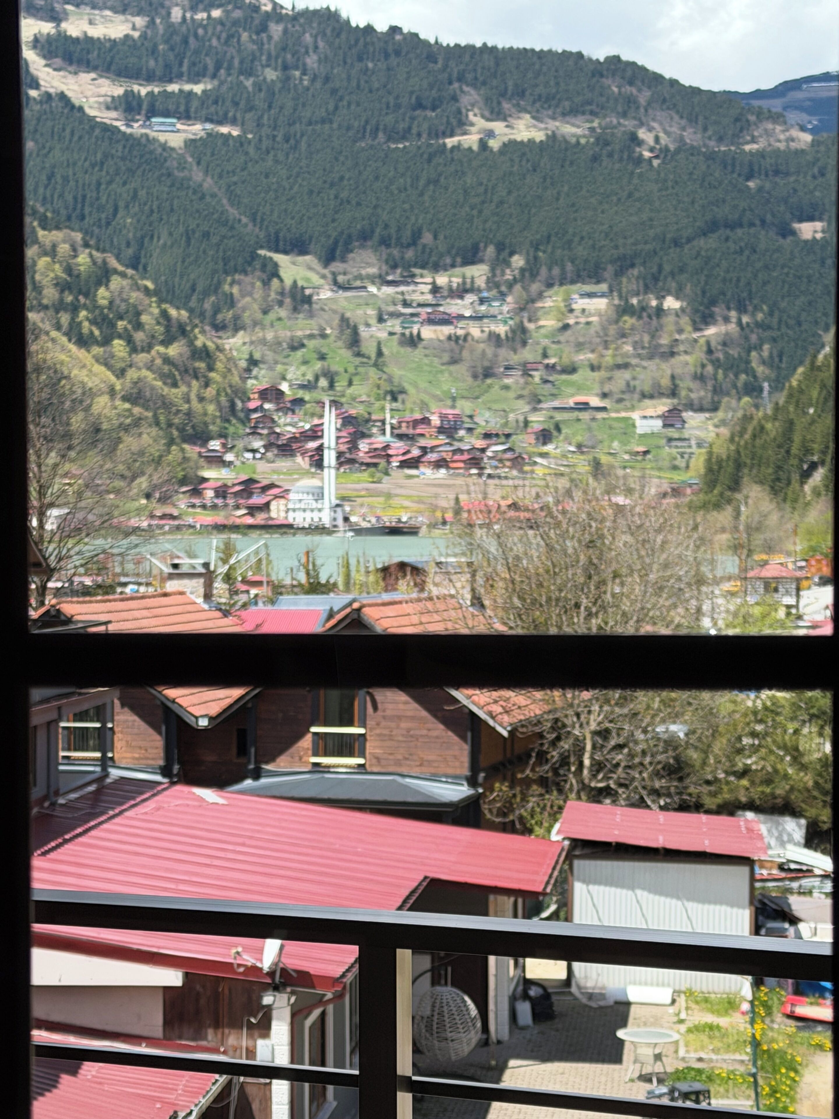Eine gebirgige Landschaft mit einem Dorf, einer markanten Kirche und Wohnhäusern mit roten Dächern.
