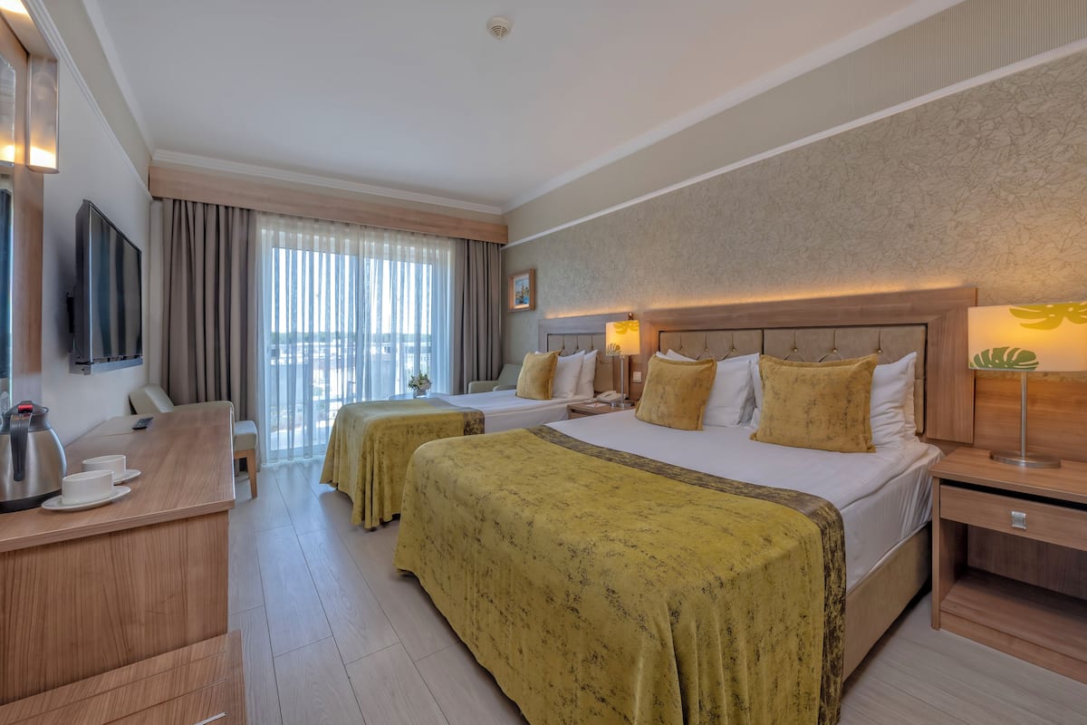 A hotel room with two beds, a desk with a kettle, and a TV.
