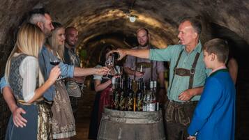 A group of people in a dimly lit, tunnel-like space with a wooden barrel filled with bottles.