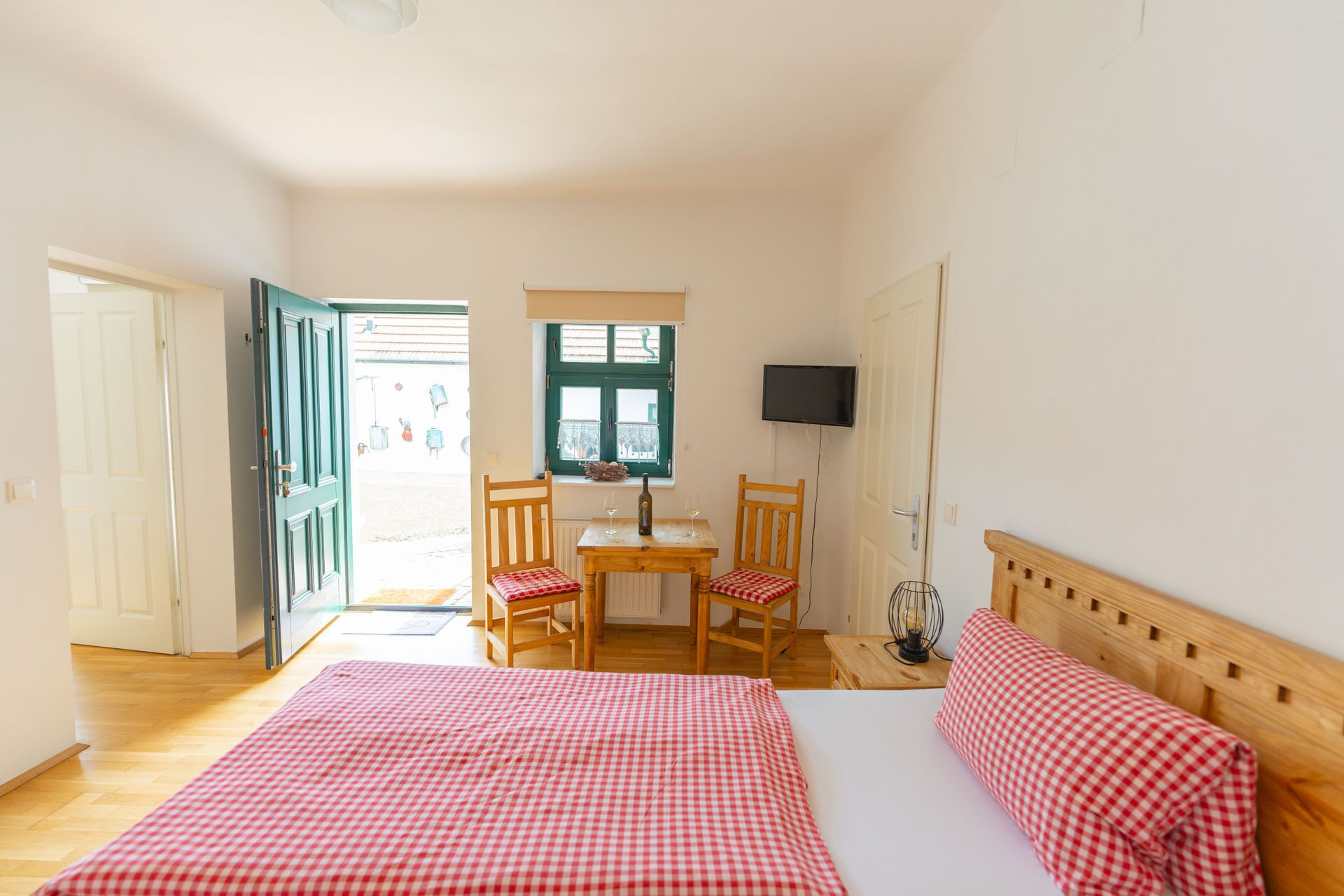 Una habitación con cama, una mesa con sillas, televisor y ventana con vistas.
