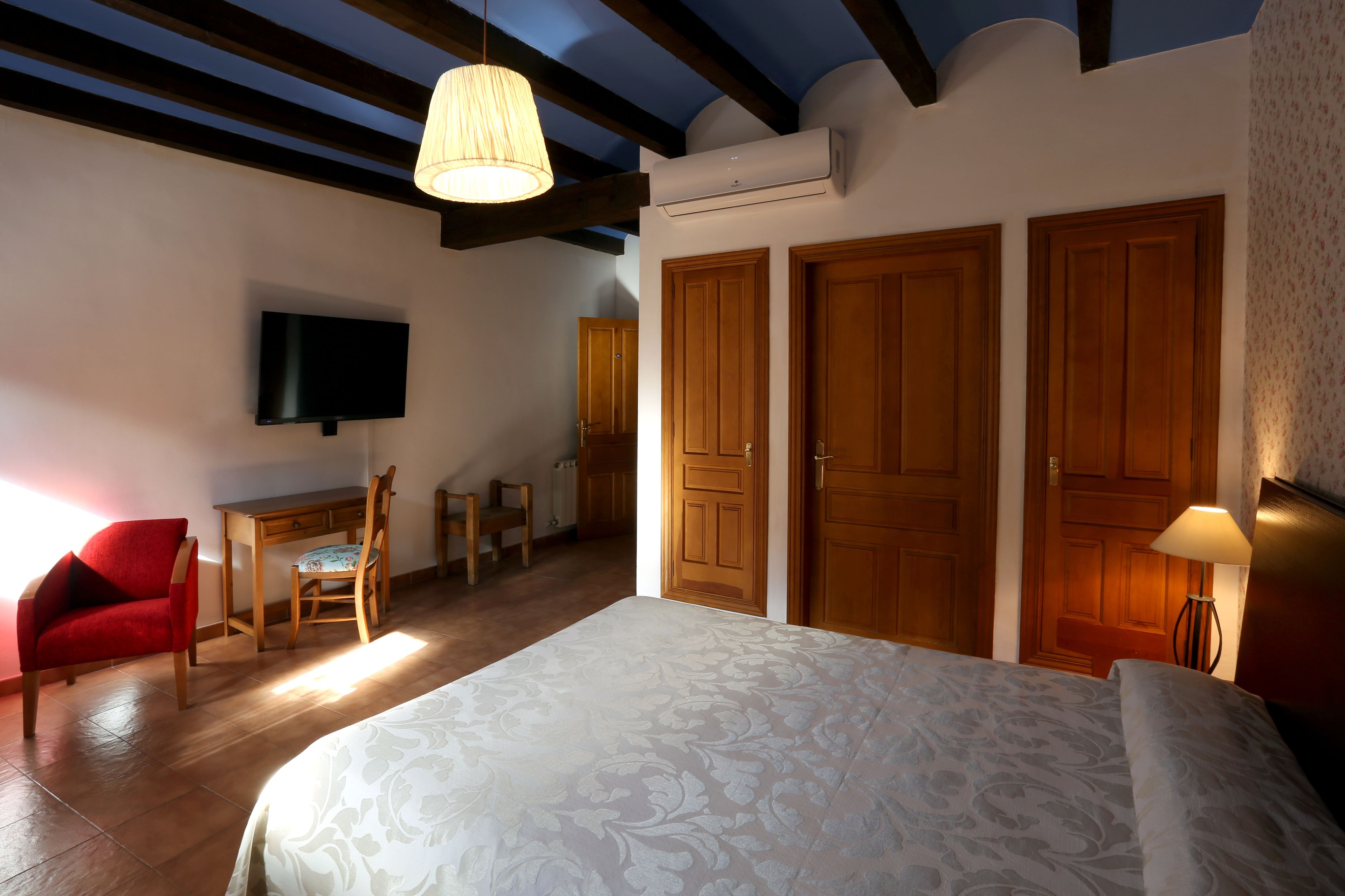 Un dormitorio con cama, escritorio, silla y televisión.