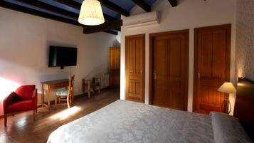 Un dormitorio con cama, escritorio, silla y televisión.