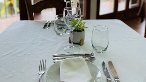 A dining table set with a white tablecloth, plates, cutlery, and a small potted plant. - Hospedería de Sádaba (Sadaba)