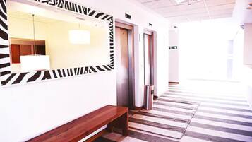 Un pasillo con piso a rayas de cebra, un banco de madera y un espejo con detalles de cebra.