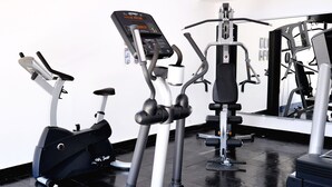 Ein Fitnessstudio mit verschiedenen Trainingsgeräten, darunter Laufbänder und Kraftgeräte, sowie einem großen Spiegel an der Wand.