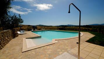 A swimming pool with stone tiles, lounge chairs, and a stone wall.