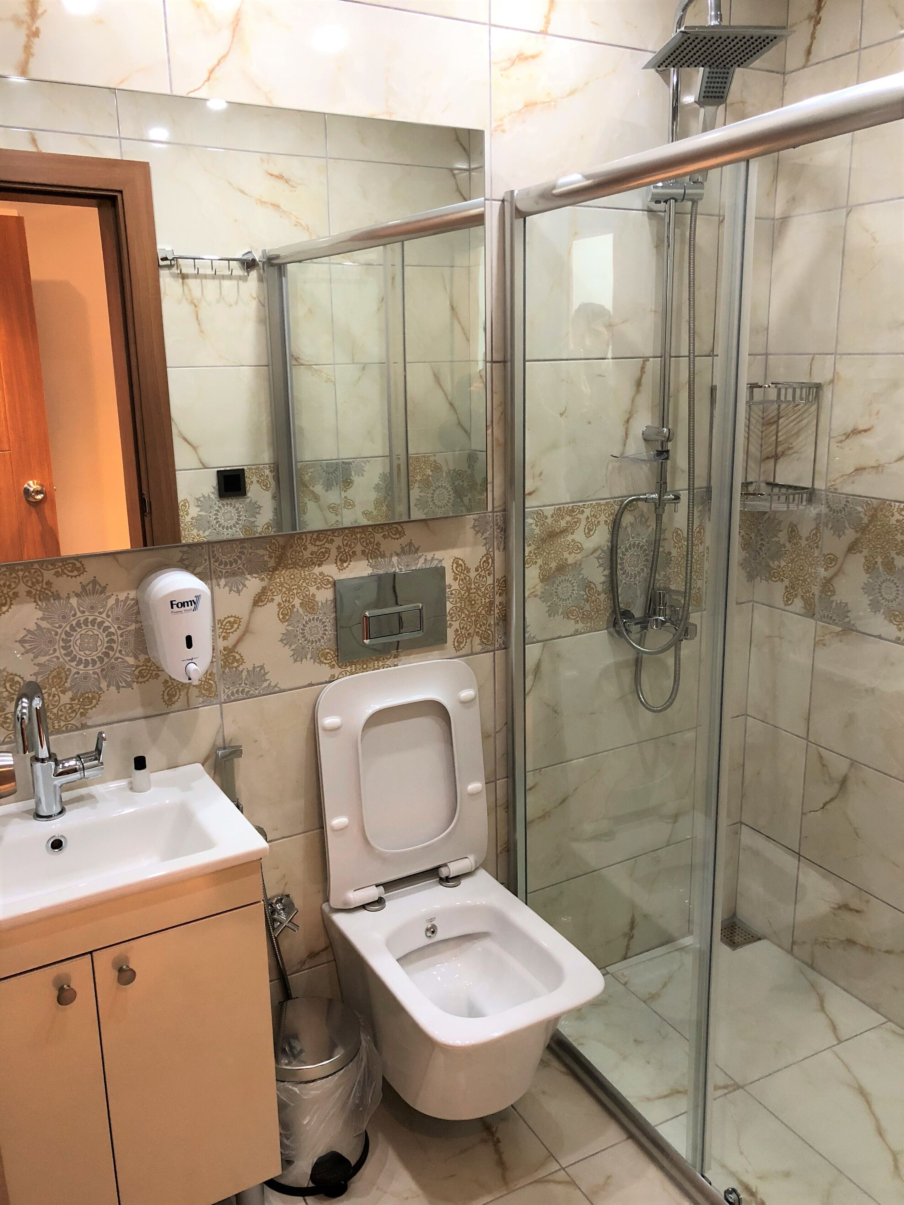 Casa de banho com sanita, lavatório e chuveiro.