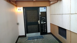 Une entrée d’immeuble avec une porte numérotée, un portail en métal et une enseigne.