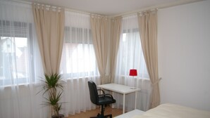 Une chambre à coucher avec un lit, un bureau, une chaise et une plante en pot.