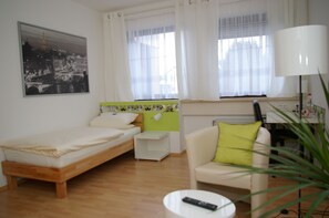 A room with a bed, a small desk, a chair, a lamp, and a plant. - CITYSLEEP Nürnberg (Nuremberg)