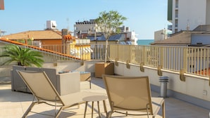 Una terraza en la azotea con dos sillones de relax, una mesita y una planta en maceta.