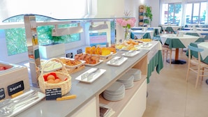 Un área de bufé con diversas opciones de comida y un cartel que indica las opciones para el desayuno.