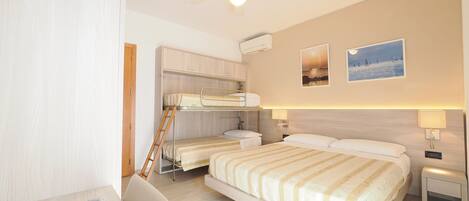 A hotel room with bunk beds, a desk, a chair, a ceiling fan, and two wall-mounted lamps.