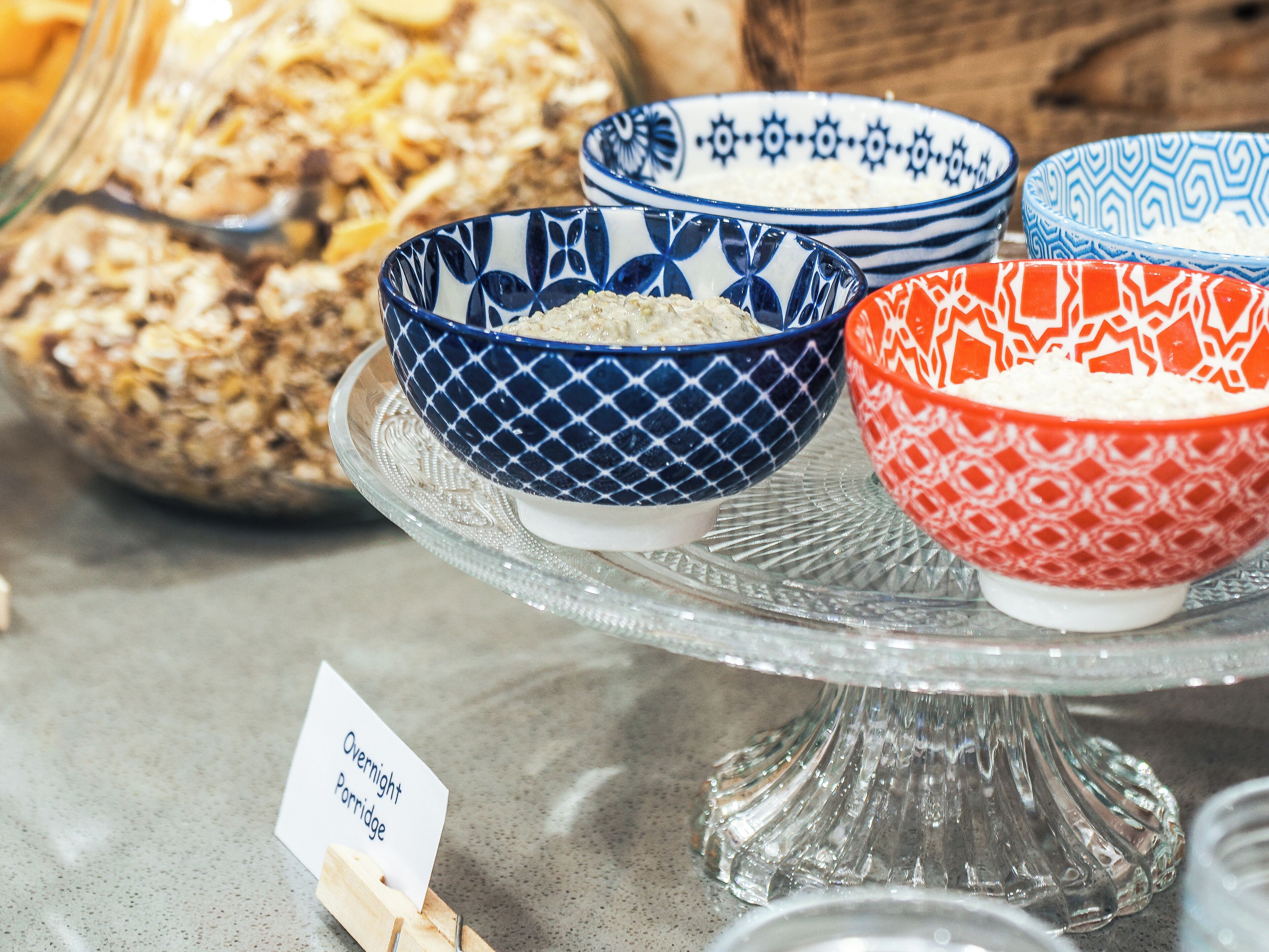 Bowls of oatmeal on a glass stand with a label reading "Overnight Porridge".