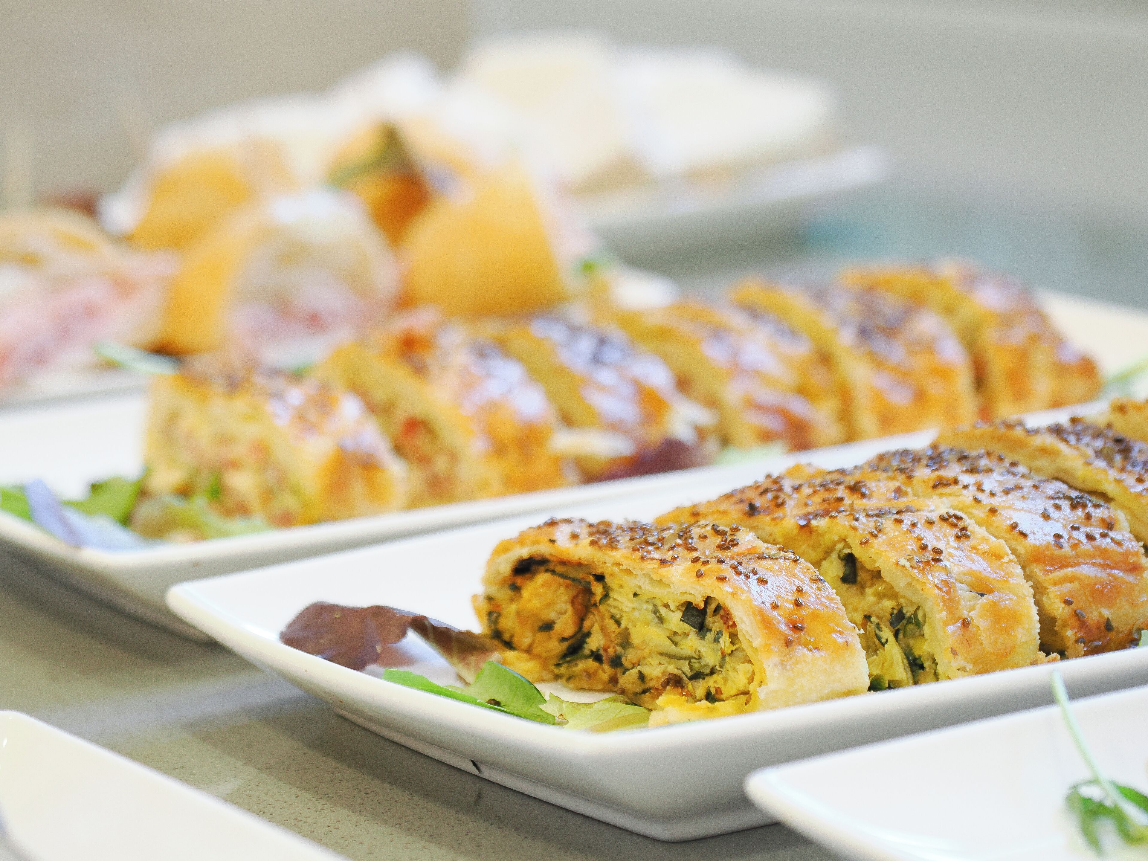 Un buffet proposant divers plats, notamment une pâtisserie enroulée à la croûte dorée et à la garniture qui semble contenir des légumes et, peut-être, de la viande.