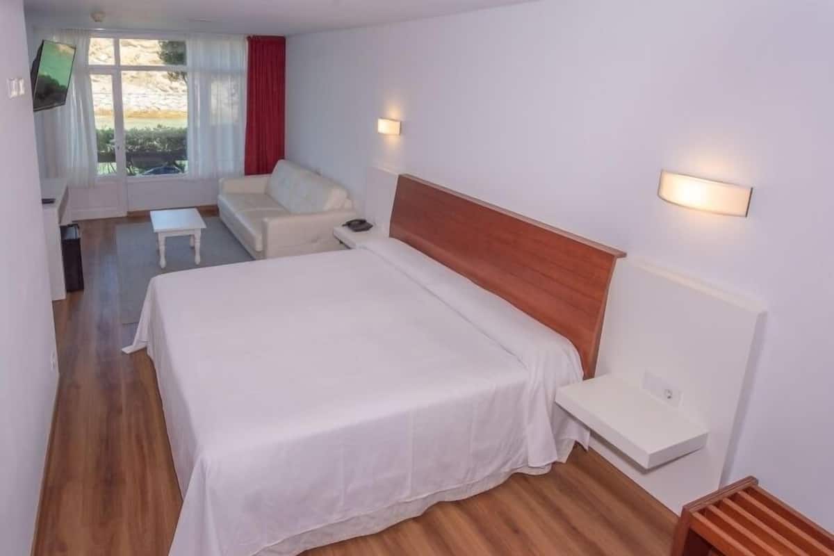A neatly arranged bedroom with a large bed, bedside tables, and a view of the outdoors.