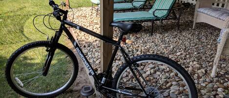 A bicycle parked near a wooden deck with outdoor seating.