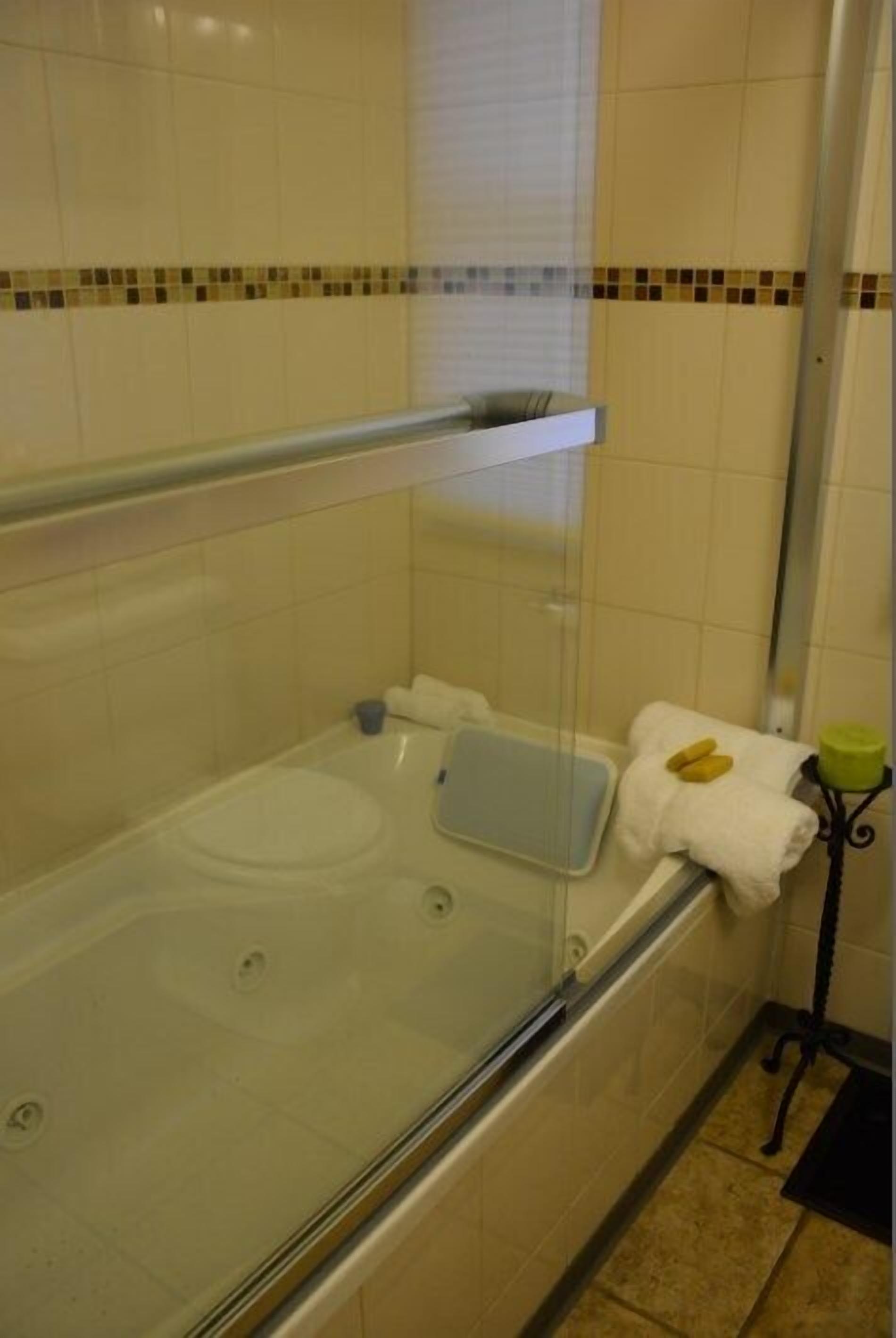 A bathroom with a bathtub, a glass shower enclosure, and a towel rack with towels.