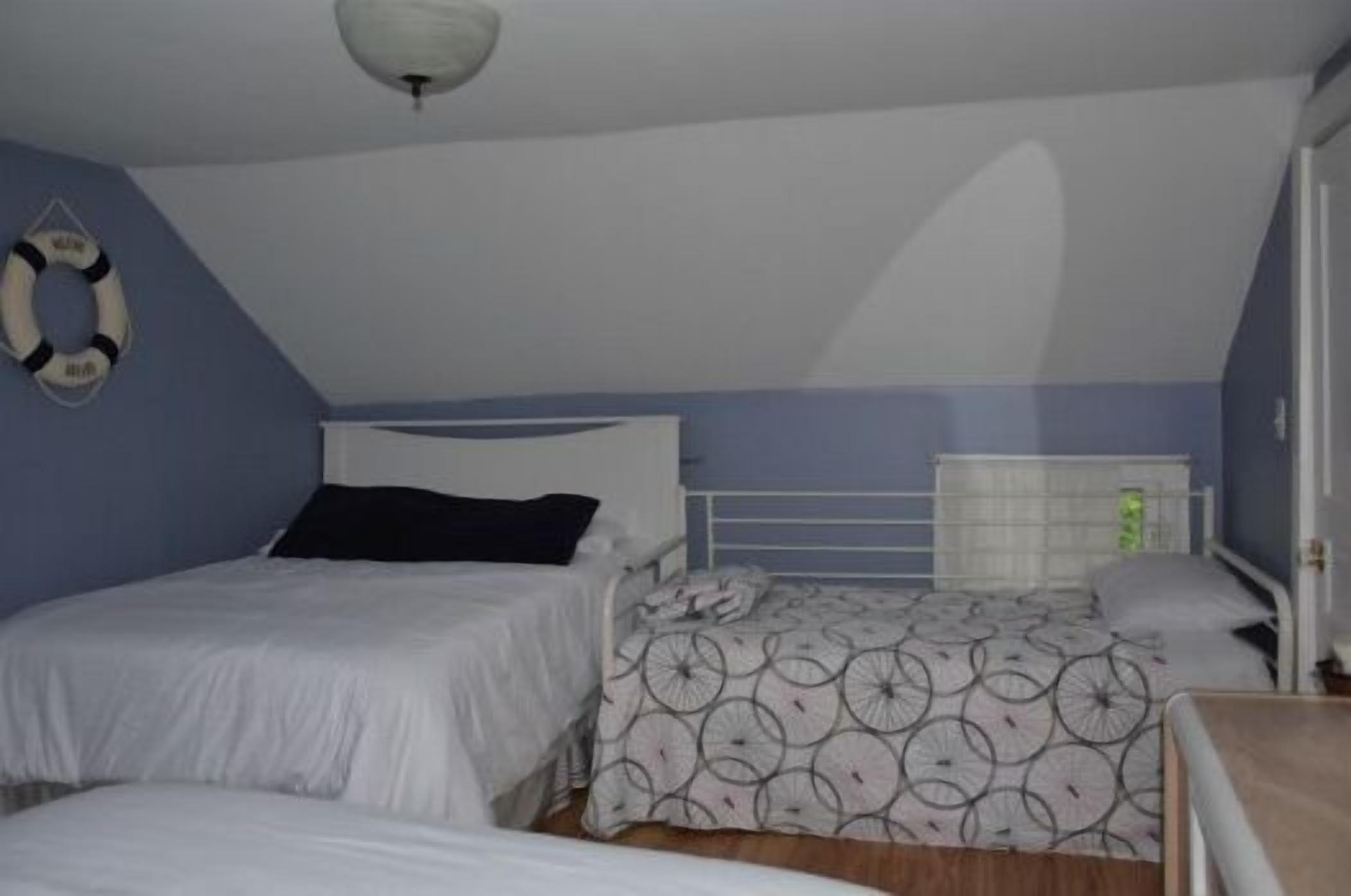 Un dormitorio con dos camas, un ventilador de techo blanco y un flotador en la pared.