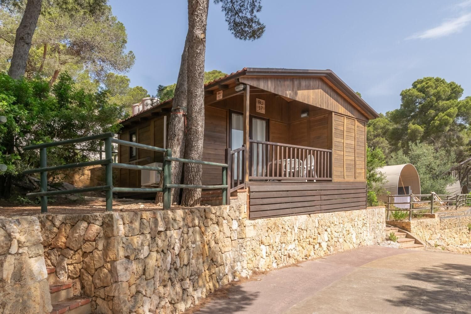 A rustic cabin with a stone foundation, wooden exterior, and a balcony with a railing.