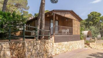 A rustic cabin with a stone foundation, wooden exterior, and a balcony with a railing.