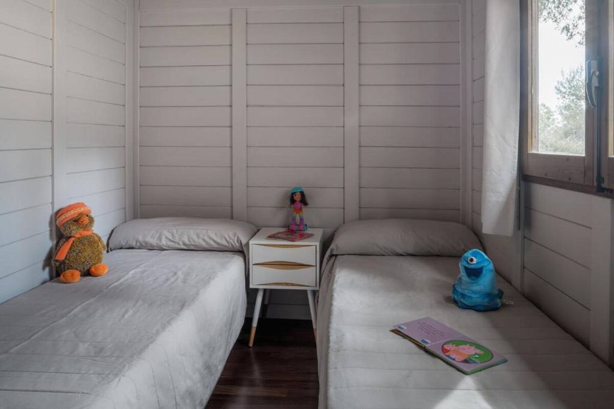 Une chambre avec deux lits simples, une table de chevet et une fenêtre.