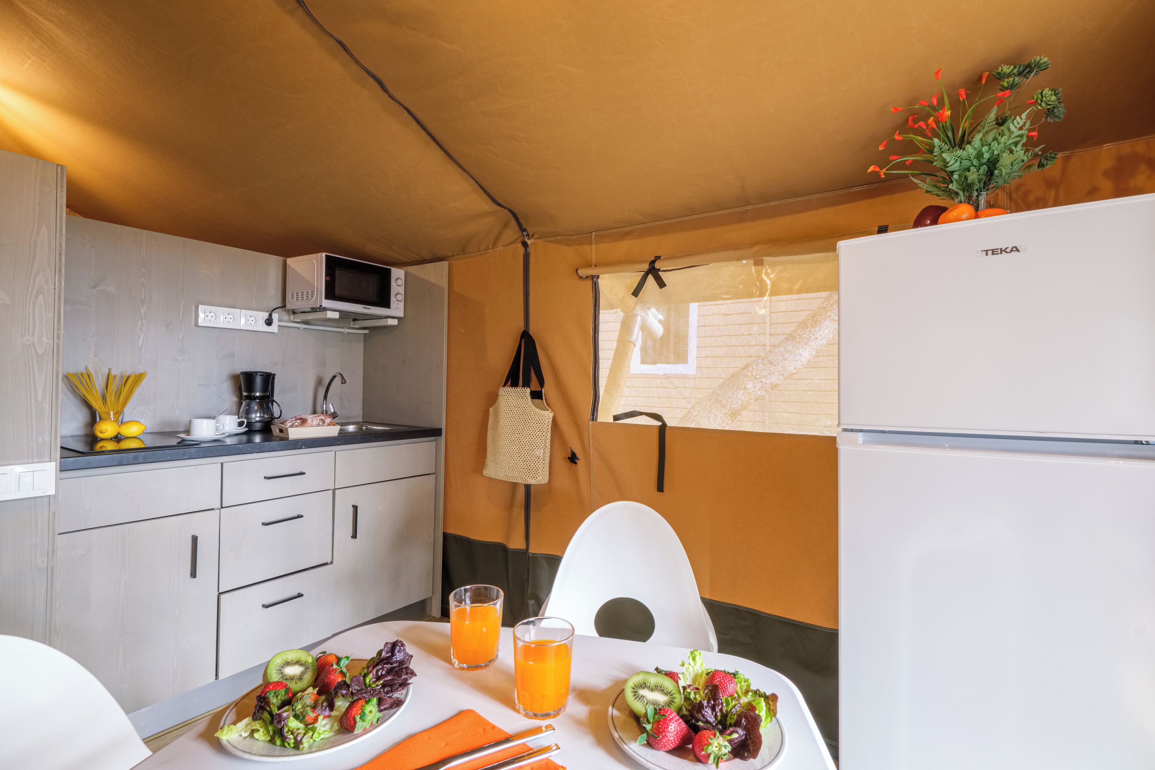 A compact kitchen with a microwave, refrigerator, and a dining area with a table set for two.
