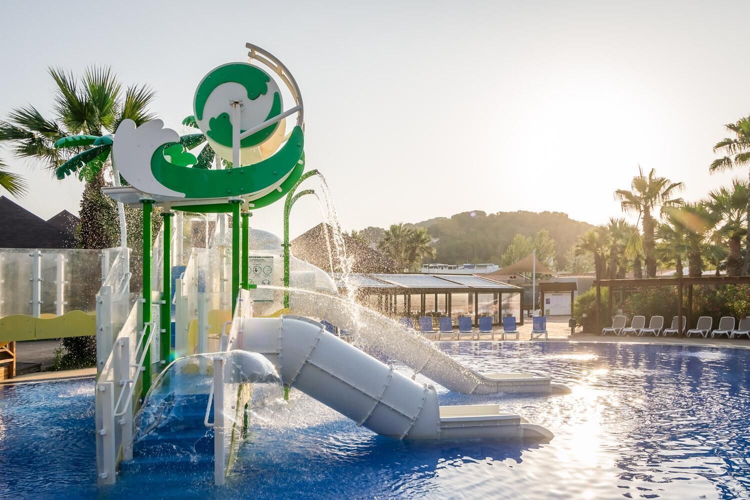 Un parc aquatique comprenant un toboggan, une piscine et un espace de détente avec des chaises longues.