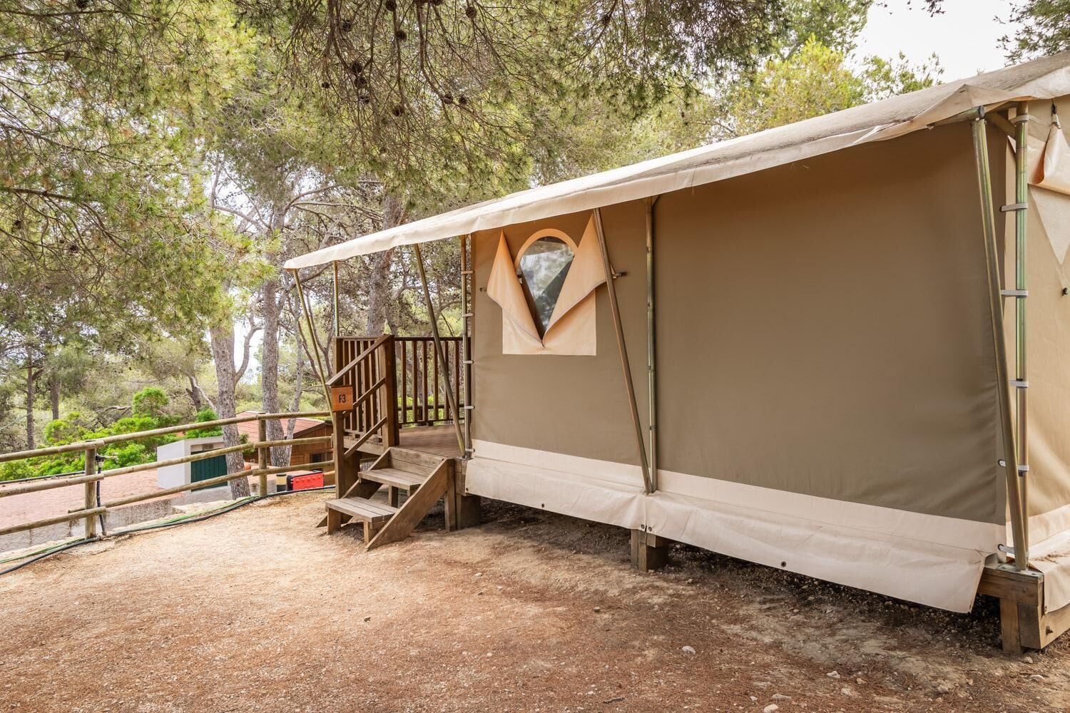 Una tenda con una scala di legno che conduce a una piattaforma, immersa tra gli alberi.