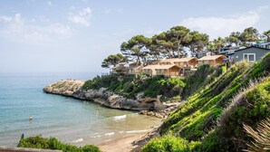 A coastal property with multiple cabins, a beach, and a rocky shoreline.