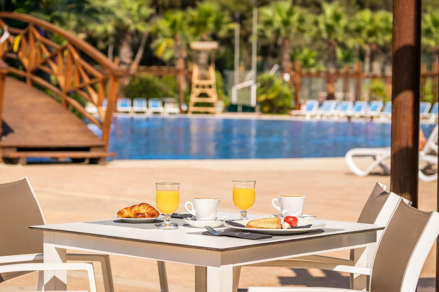 Ein Tisch mit Frühstücksangeboten und Blick auf das Schwimmbecken.
