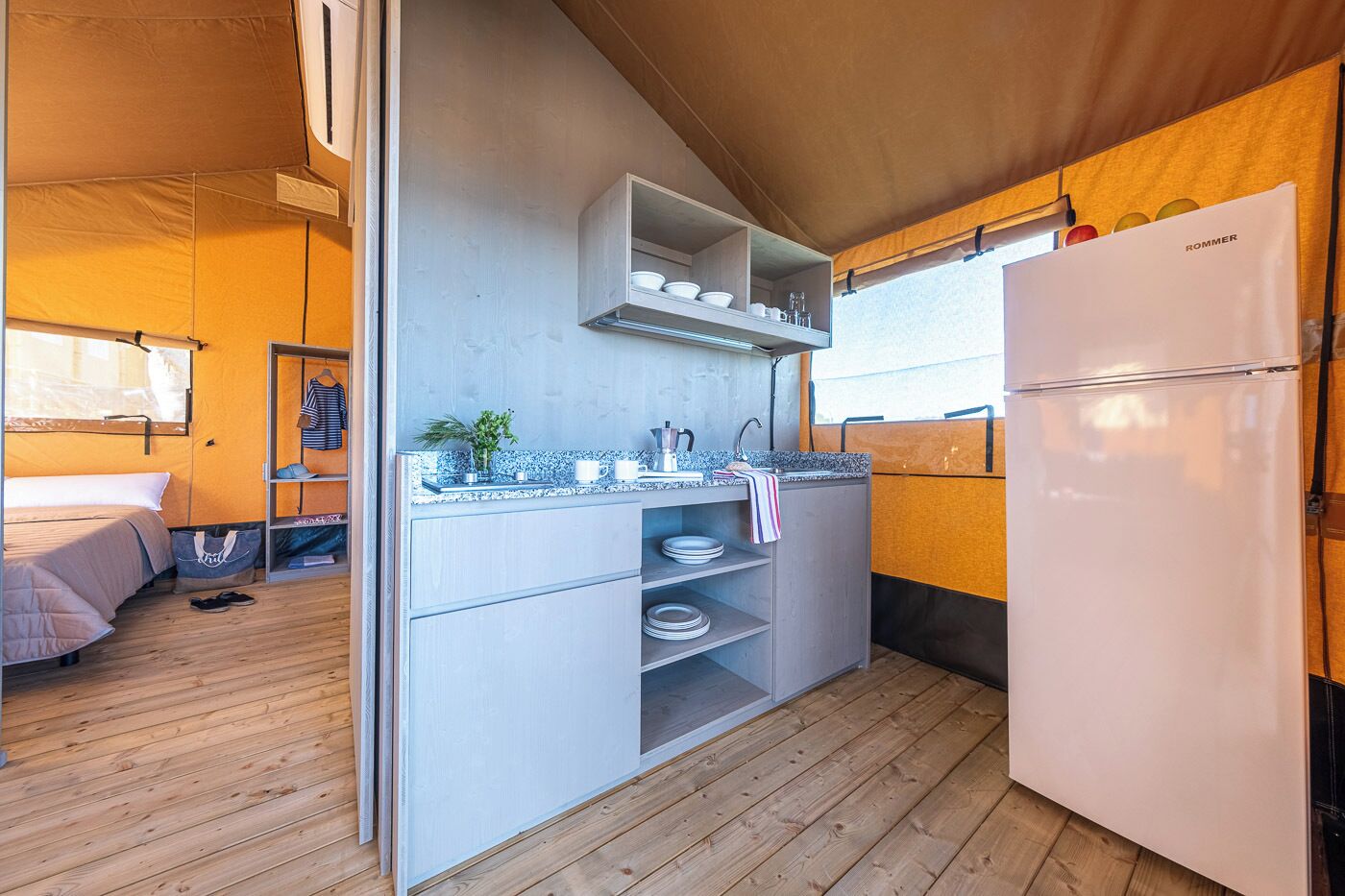 Una cocina compacta con refrigerador empotrado, un lavamanos y una encimera con varios objetos.