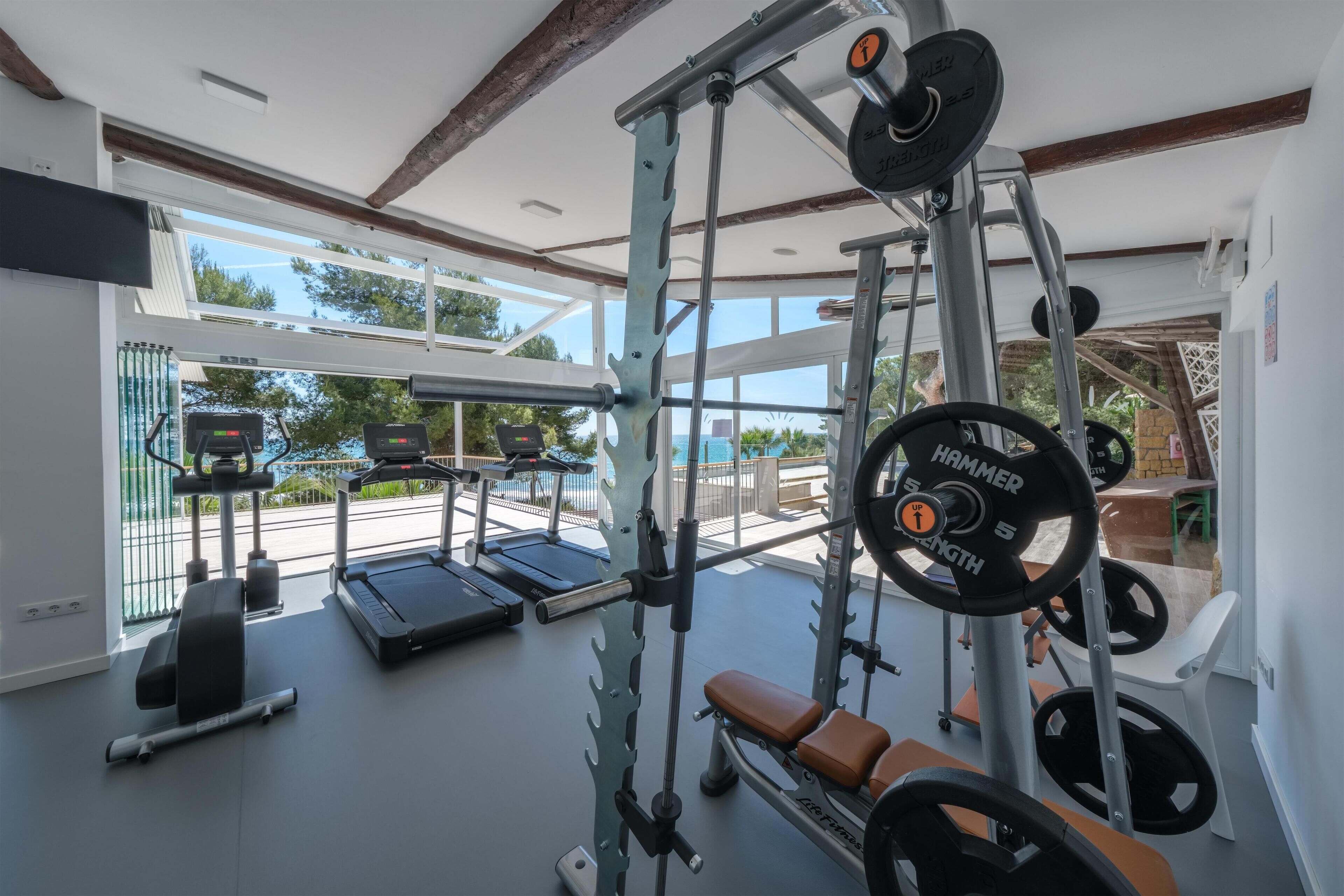 Een fitnessruimte met loopbanden, krachtherinneringen en een bank.
