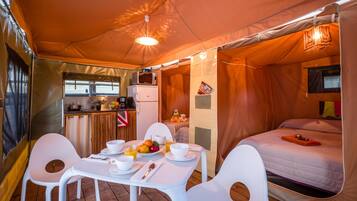 Allotjament en tenda amb zona de menjador, cuina americana i llit.