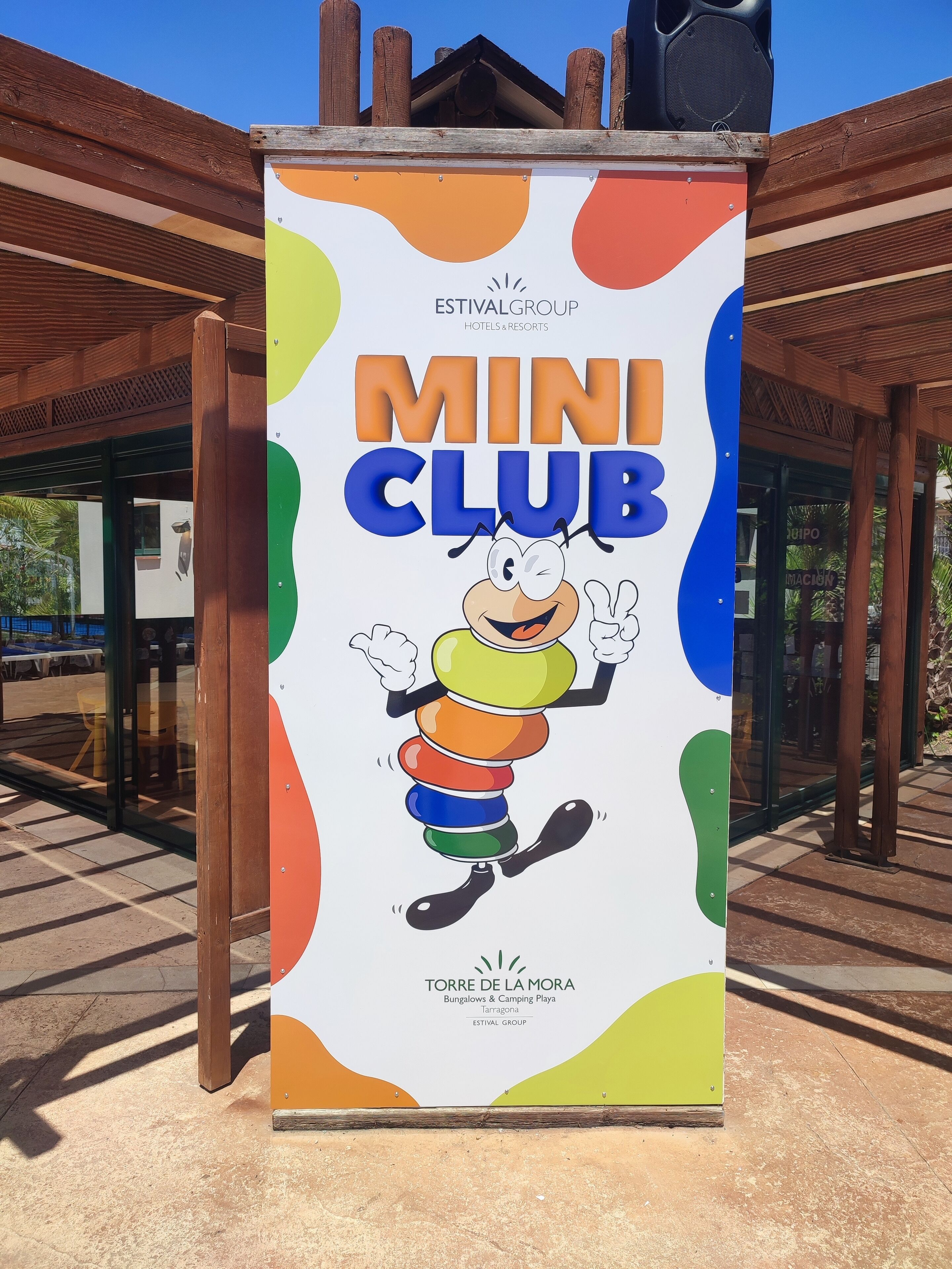 A sign for the Mini Club at Torre de la Mora, part of the Estival Group, featuring a cartoon character and colorful design elements.